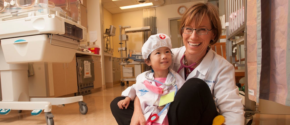 Woman laughs with a child in a hospital